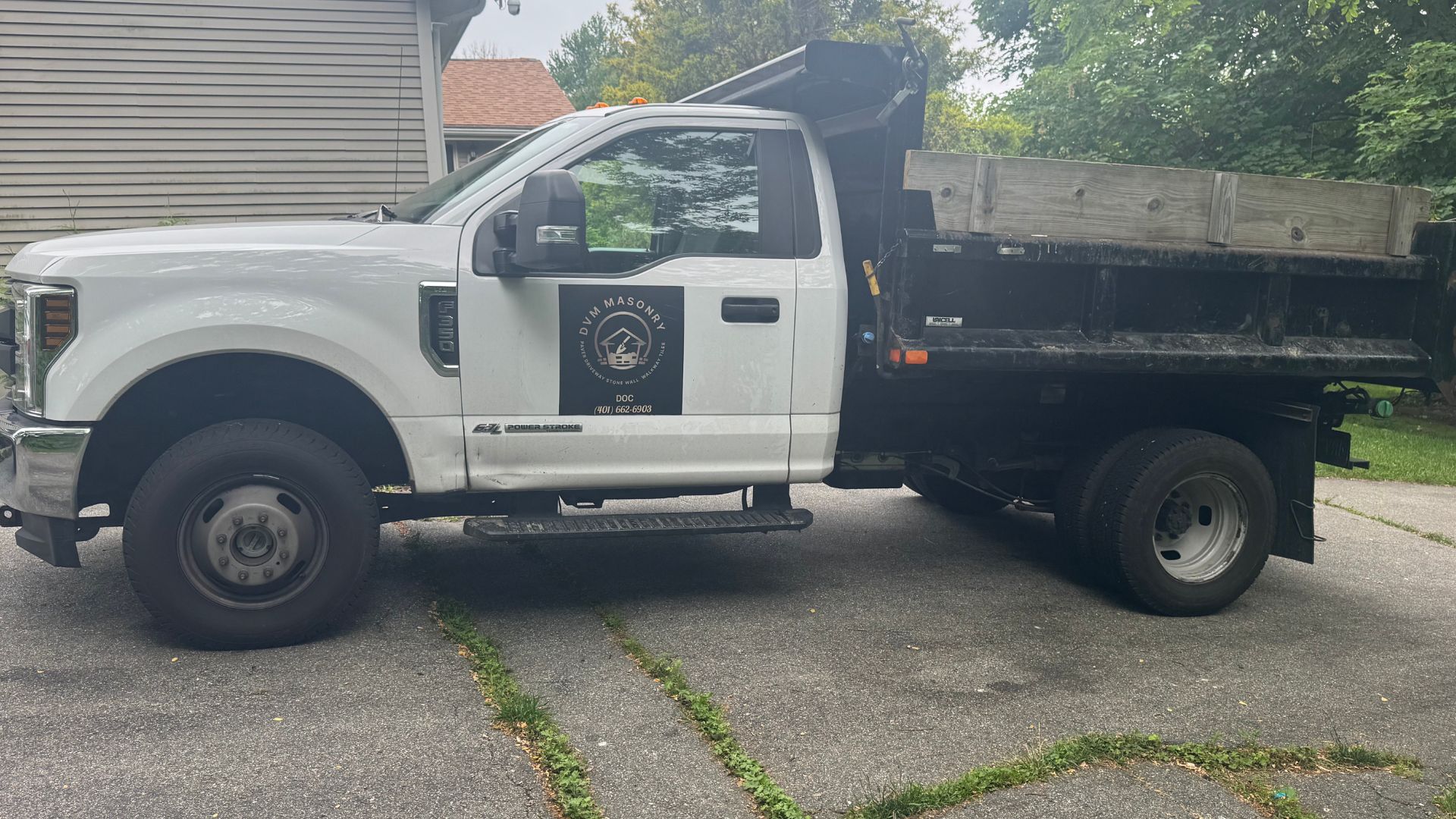 White dump truck with DFM Masonry logo parked on residential street