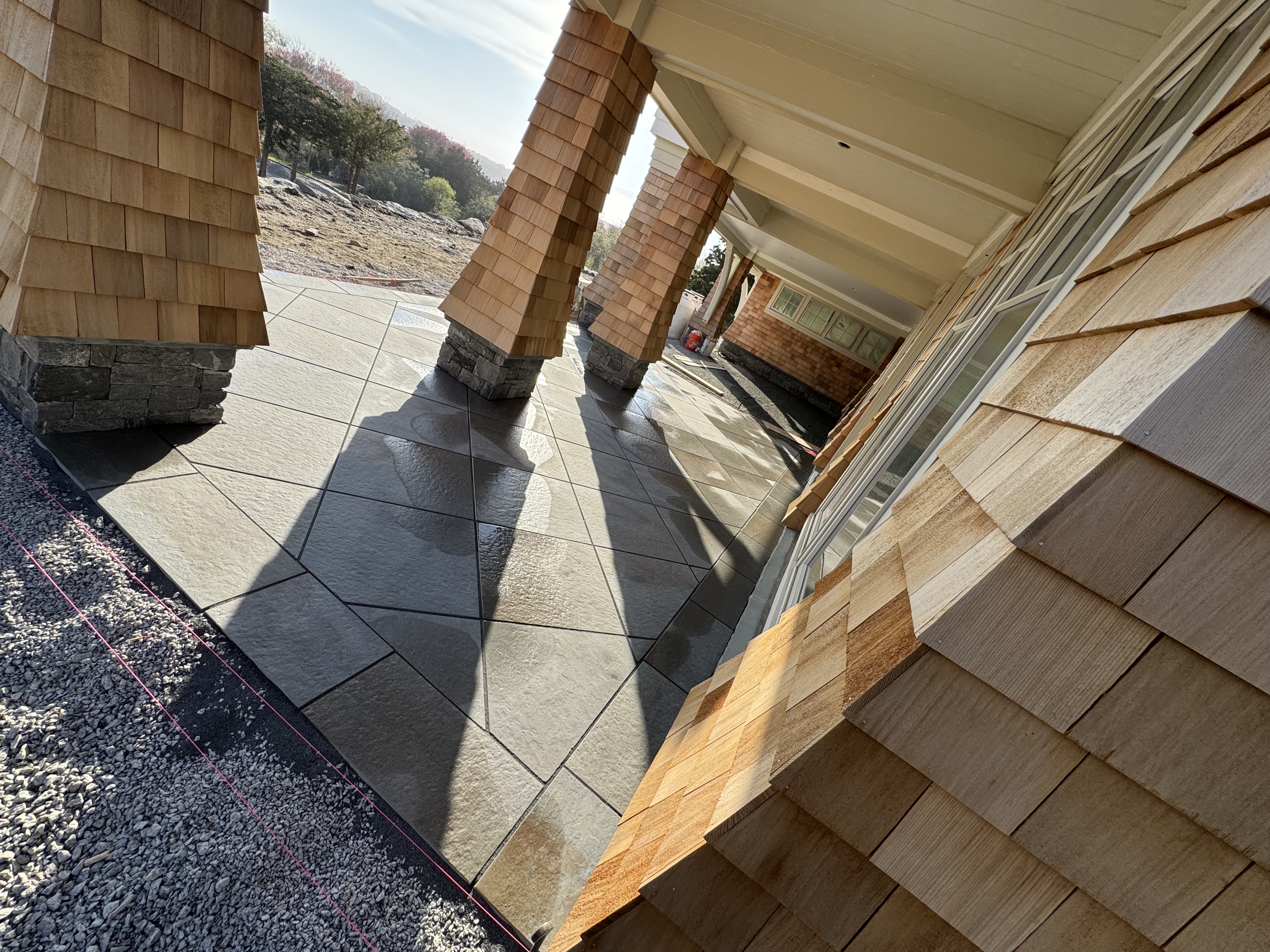 Modern building exterior with wooden shingles and stone column shadows