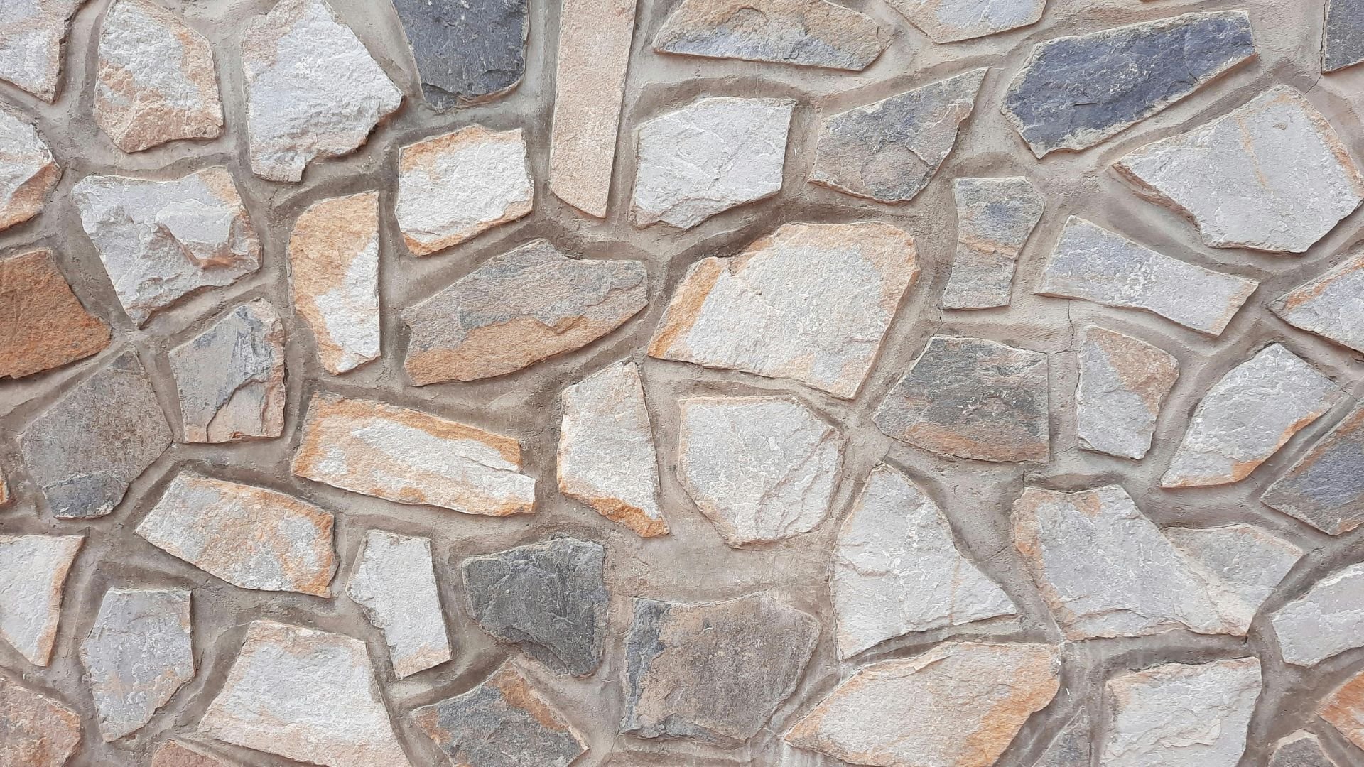 Irregular stone wall with white, gray, and orange-tinted rocky texture