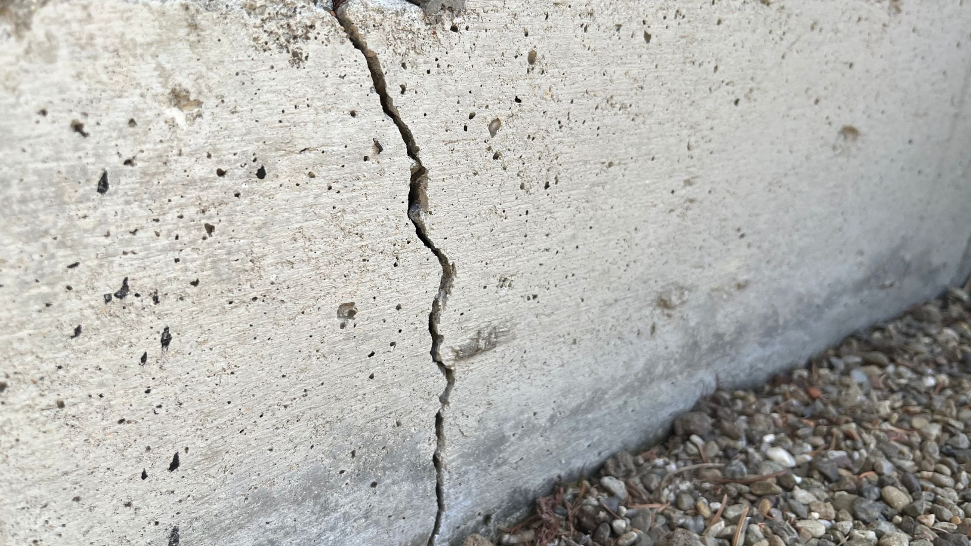 Large vertical crack running through a weathered concrete surface